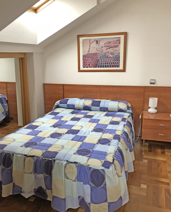 Fotografía dormitorio con una cama grande en buhardilla Apartahotel Ribera
